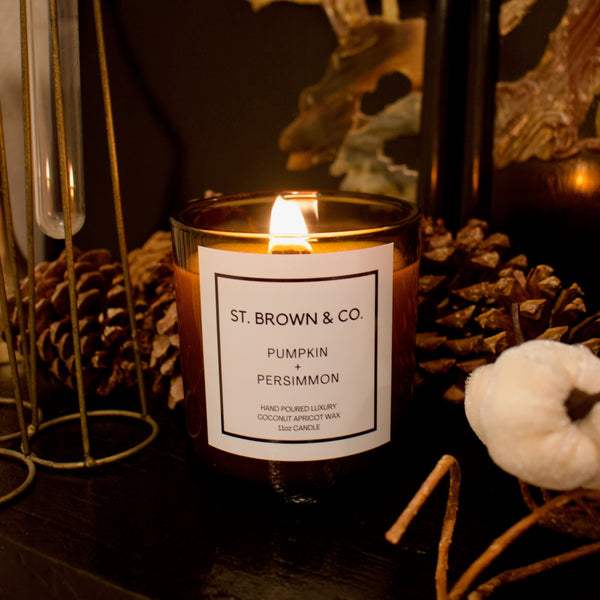 Candle with 'St. Brown & Co.' label on a dark surface with decorative elements